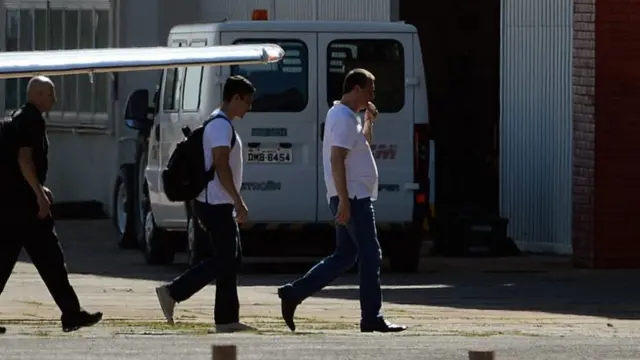 Joesley Batista deixando um avião usando camiseta branca e calça jeans, acompanhadoapk vaidebetpoliciais