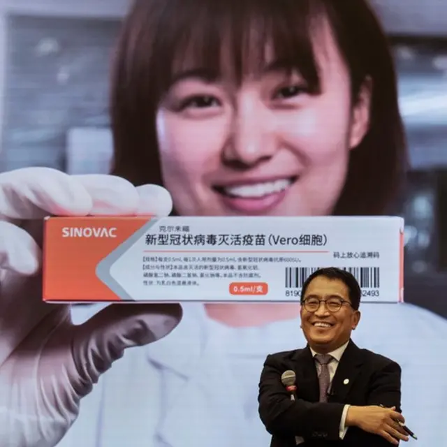Yin Weidong, presidente de la empresa Sinovac frente a una imagen de la vacuna de su laboratorio