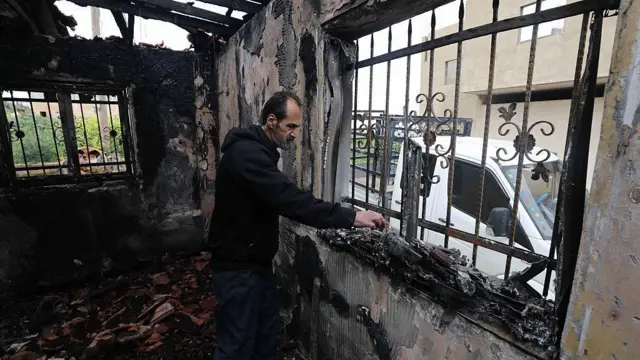 Un hombre entre los escombros de una casa incendiada