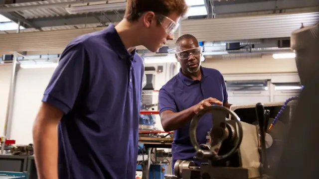 Сотрудник фабрики показывает школьникам, как работает токарный станок