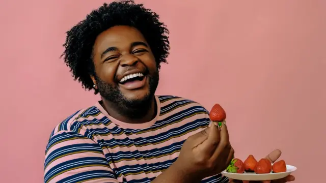 Homme noir qui tient une fraise