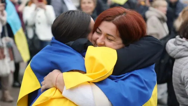 Dos mujeres con las banderas de Ucrania se abrazan en Odesa.