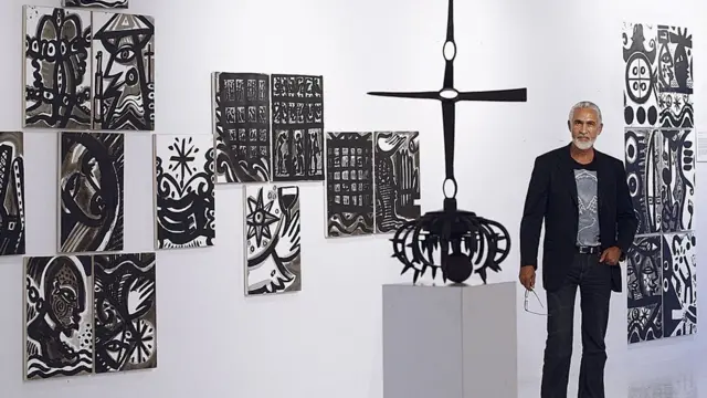 L'artiste haïtien Philippe Dodard se tient à côté de son œuvre,'Memory in Motion'.