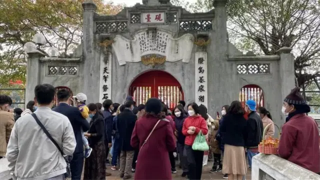 Đền Ngọc Sơn chỉ mở cửa đón từng tốp 10 người đi lễ mỗi lượt nên khá nhiều người phải đợi bên ngoài.