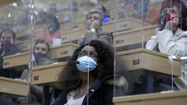 People sitting in separate perspex cubicles react as they bid for flowers during an action inside the Multiflora warehouse in Johannesburg, on May 8, 2020. - Multiflora is a specialised flower auction space where some 300 million flower stems are auctioned and sold into the flower market in South Africa.