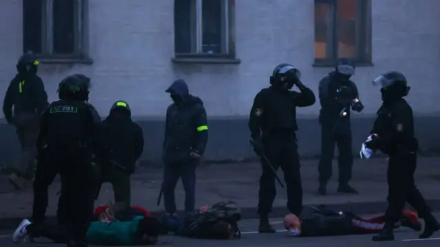 Police hold demonstrators face-down on the floor on 25 October