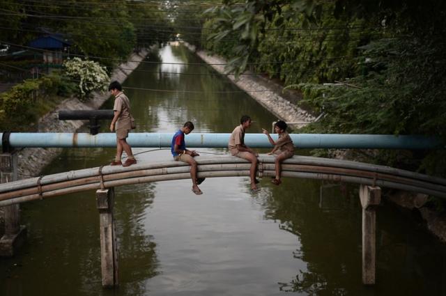 Students play on the water pipes after school time near the Government House in Bangkok, Thailand.