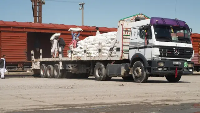 Поезд вагонидан ун қопларини бк автомобилига оратётган афғонлар