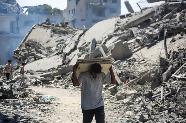Warga Palestina berjalan di sepanjang jalan yang dipenuhi puing-puing di kawasan Tuffah, Kota Gaza.
