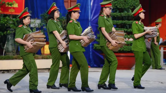 Policewomen carry case report files on the female prisoners to be freed at a local jail in the suburbs of Hanoi on August 31, 2015.