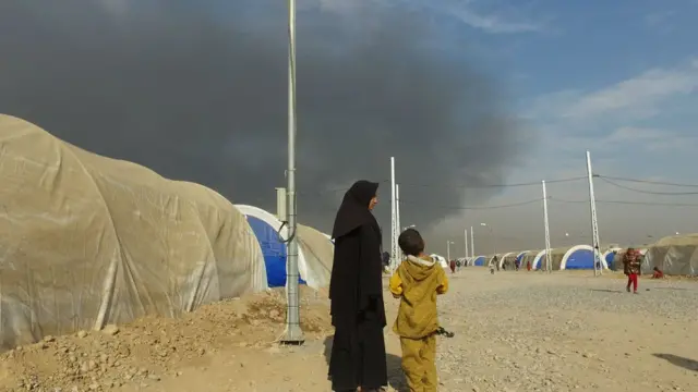 سحب دخان تتصاعد من بئر نفط تم تفجيره غير بعيد عن مخيم أربيل للنازحين