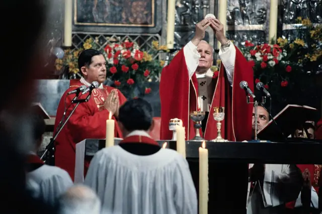 Paus Yohanes Paulus II mengangkat Ekaristi selama misa di Polandia.