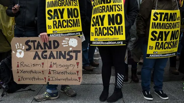 Demonstrators hold signs before the inauguration of President-elect Donald Trump in Washington.