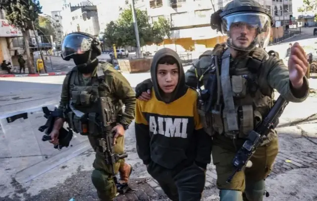 हेब्रान में 2022 में एक प्रदर्शन के दौरान एक किशोर को हिरासत में लेकर जाते इसराइली सैनिक