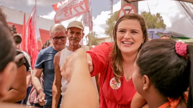 Fotografia colorida mostra Marília Arraes, uma mulher branca de cabelo comprido e loiro