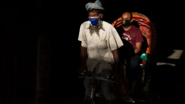 ঢাকার কাছে নারায়নগঞ্জ-এ মাস্ক পরিহিত রিক্সাচালক এবং আরোহী, ২৯-০৩-২০২০।