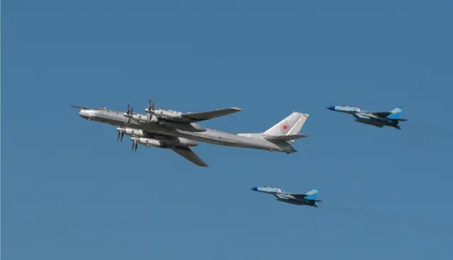 Pesawat pembom startegis TU-95 dikawal pesawat tempur MiG-29 dalam sebuah demponstrasi terbang untuk memperingati ulang tahun Angkatan Udara Rusia.