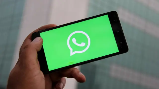 Homem segura celular com logo do WhatsApp na tela