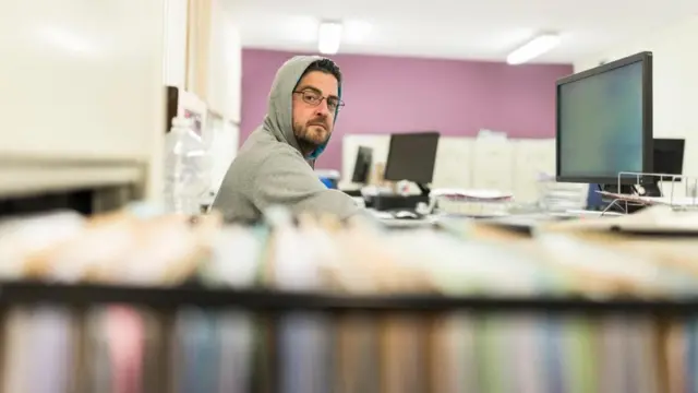 شاب يجلس أمام جهاز الكمبيوتر في مكتبه