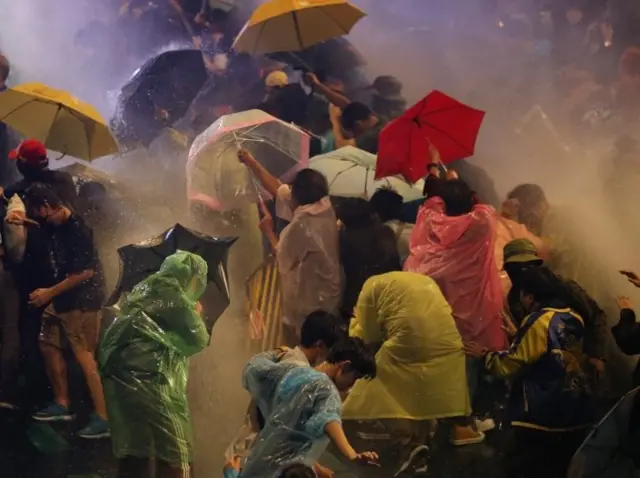 Pro-democracy protesters react as riot police fire water canons during an anti-government protest in Bangkok, Thailand, 16 October 2020.