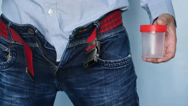 Un hombre con un bote para depositar esperma.