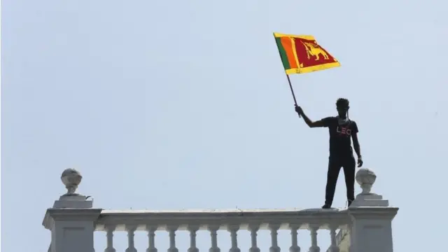 A protester waves the national flag as protesters storm the Prime Minister"s office in Colombo, Sri Lanka, 13 July 2022.