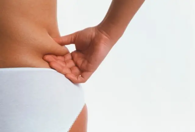 Людина торкається складки на талії