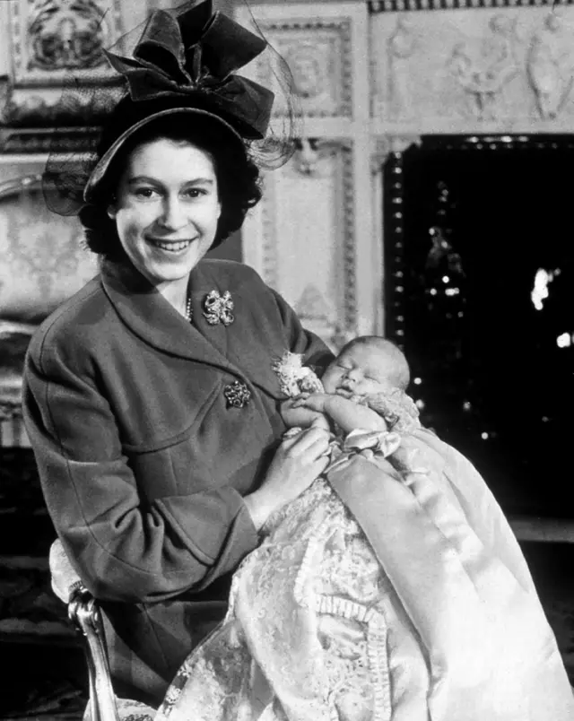 Sua Majestade Rainha Elizabeth 2ª fotografada quando era princesa Elizabeth, com seu primogênito (agora rei Charles 3º) em seu batismo em 1948