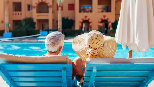 Pareja adulta frente a la piscina de un hotel