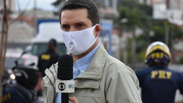 Repórter da Globodupla sena de páscoa ano 2024máscara e segurando microfone da emissoradupla sena de páscoa ano 2024estrada