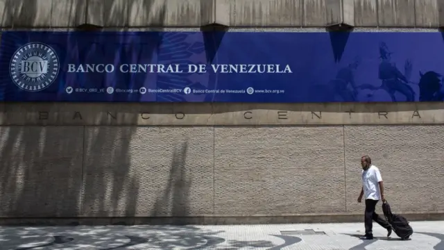 Un hombre camina frente a la fachada del Banco Central de Venezuela