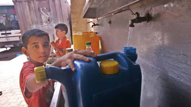 Un jeune Palestinien verse de l'eau dans un récipient provenant d'une usine de désalinisation