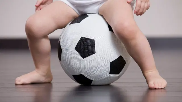 Ребенок на футбольном мяче