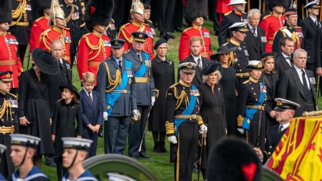 De izquierda a derecha: la princesa de Gales, la princesa Charlotte, el príncipe George, el príncipe de Gales, el rey Carlos III, el duque de Sussex, la reina consorte, la duquesa de Sussex, la princesa Ana, la princesa Beatrice, Peter Phillips y el duque de York en un momento de la procesión por las calles de Londres.