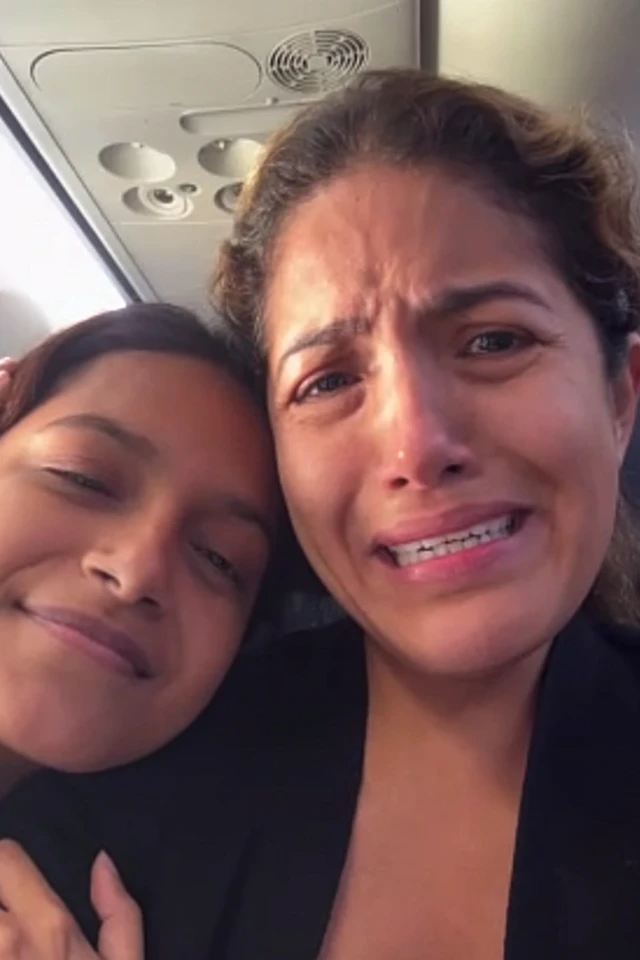 Una mujer y su hija dentro de un avión. La joven sonríe y su madre llora.