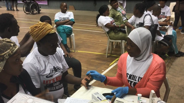 Woman wey dey check her blood sugar with medical volunteer