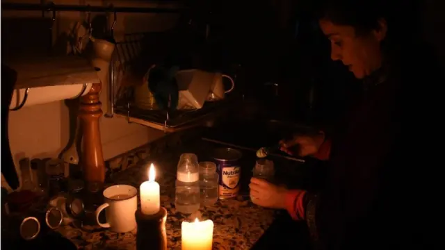 Mulher acende velas para ter luz durante o apagão na Argentina