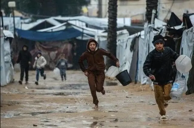 صبيان يسعيان للحصول على مياه شرب بين الخيام