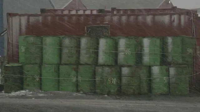 Fuerte nevada y barriles verdes al fondo