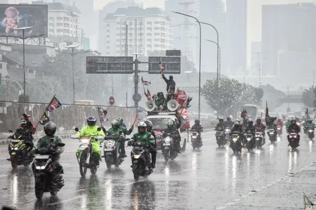 Pengemudi taksi motor online tiba di tengah hujan untuk memprotes, menuntut perlindungan kesejahteraan yang lebih baik dan penyelidikan penuh atas kematian seorang pengemudi selama rapat umum Agustus, di pintu masuk utama kompleks parlemen di Jakarta pada 17 September 2025