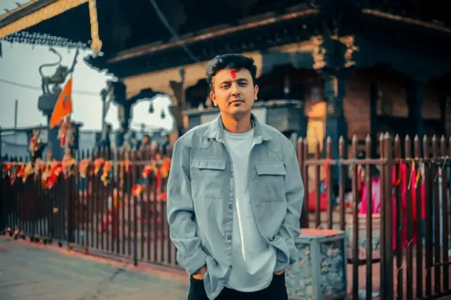 रुटिन अफ नेपाल बन्दका संस्थापक भिक्टोर पौडेल, पृष्ठभूमिमा मन्दिर।