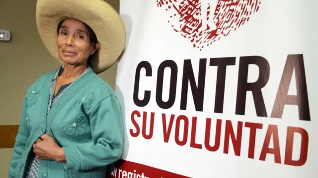 Esperanza Huayama junto a un cartel que dice "contra su voluntad"