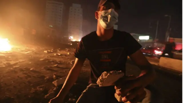 ফিলিস্তিনি এক যুবক পাথর ছোড়ার প্রস্তুতি নিচ্ছে