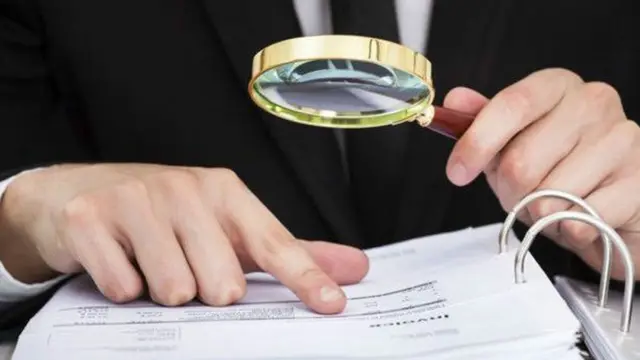 Hombre que estudia un documento con una lupa.