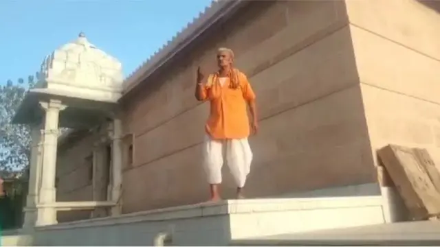 గుళ్లోకి రావద్దంటూ హెచ్చరిస్తున్న పూజారి