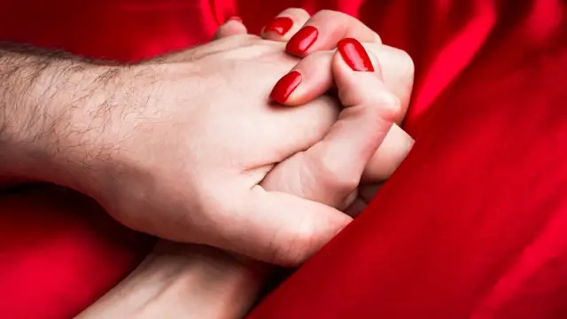 Manos agarradas en cama roja