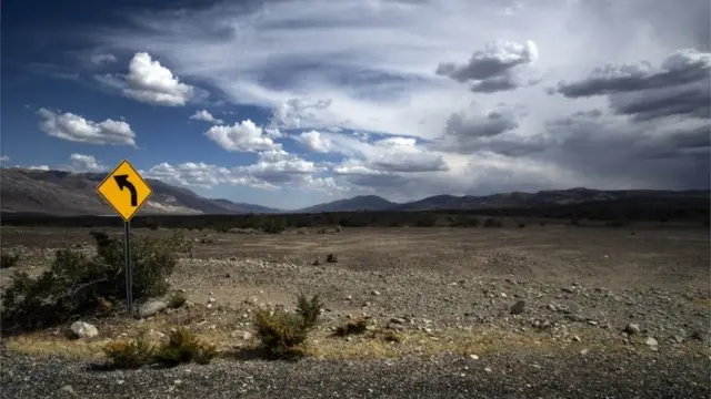 Paisagem desértica do Vale da Morte, sob um céu azul com nuvens brancas