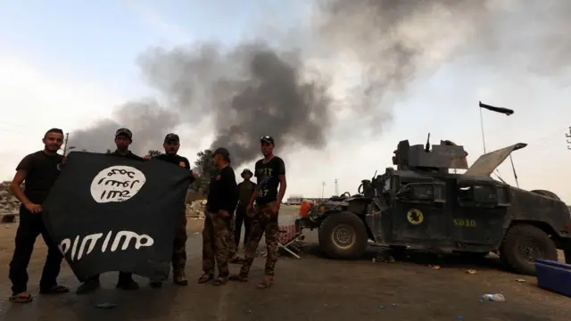 Agentes de seguridad iraquíes muestran una bandera de EI, tras recuperar una zona bajo control de los islamistas.