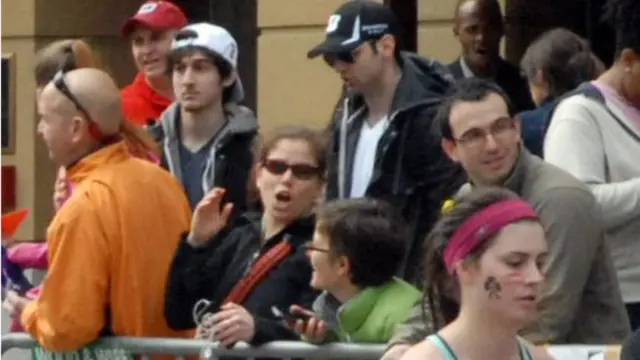 Джохар Царнаев (второй слева) и Тамерлан Царнаев (в центре) стоят в толпе на финише Бостонского марафона, где впоследствии прогремел взрыв, в совершении которого они признаны виновными