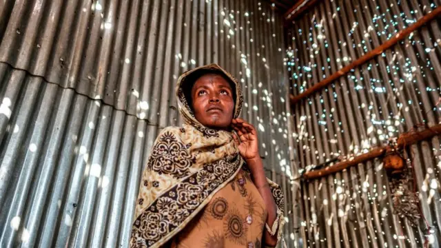 A woman stands in a metal sheet room that was damaged by shelling, in Humera, Ethiopia, on November 22, 2020.